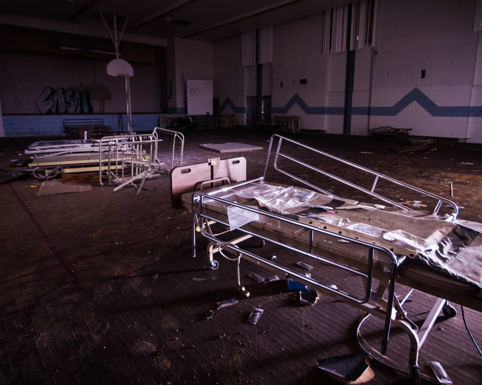 In a creepy urban exploration photograph of the Grace Hospital in St. John's, Newfoundland, an old broken down hospital bed is seen in a dilapidated gymnasium of the hospitals nurses residence.