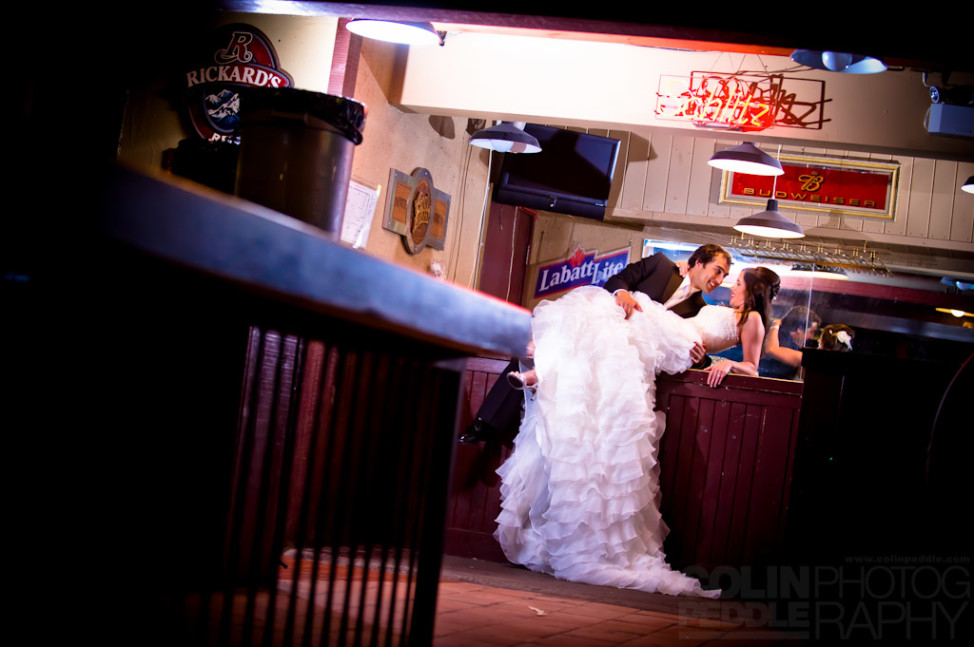 A newlywed couple makes out on a bar counter on their wedding day.