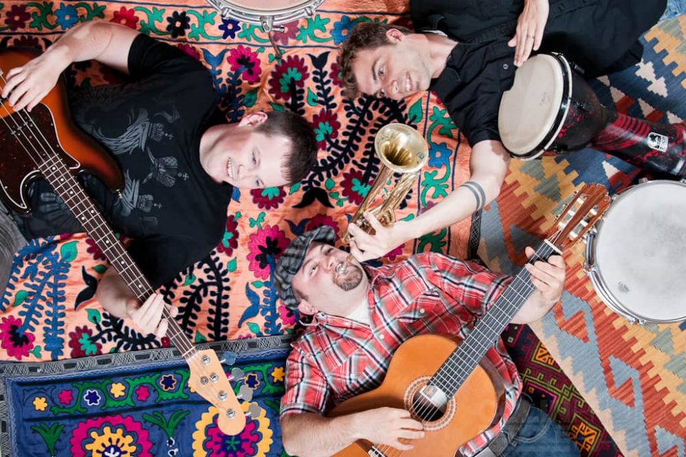 Three musicians lay on their backs while playing their instruments in this humerous photograph