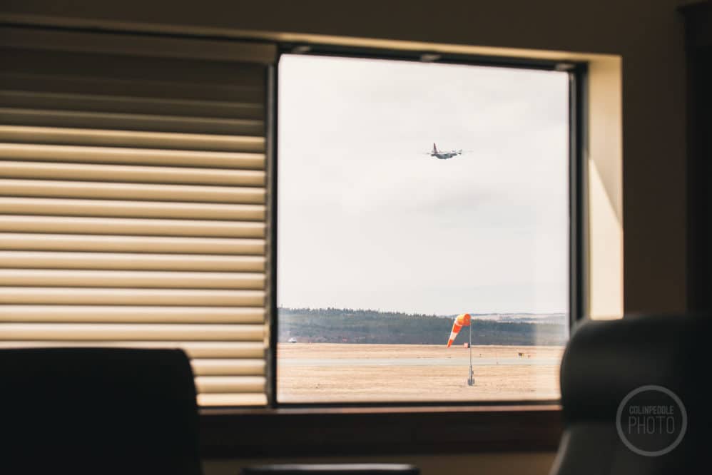 A flight departs CYYT through the office windows
