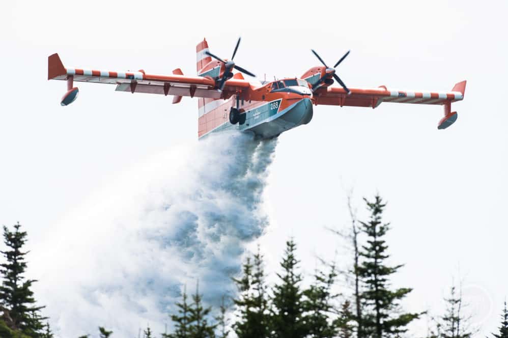 A water bomber drops a load of water on a forest fire.