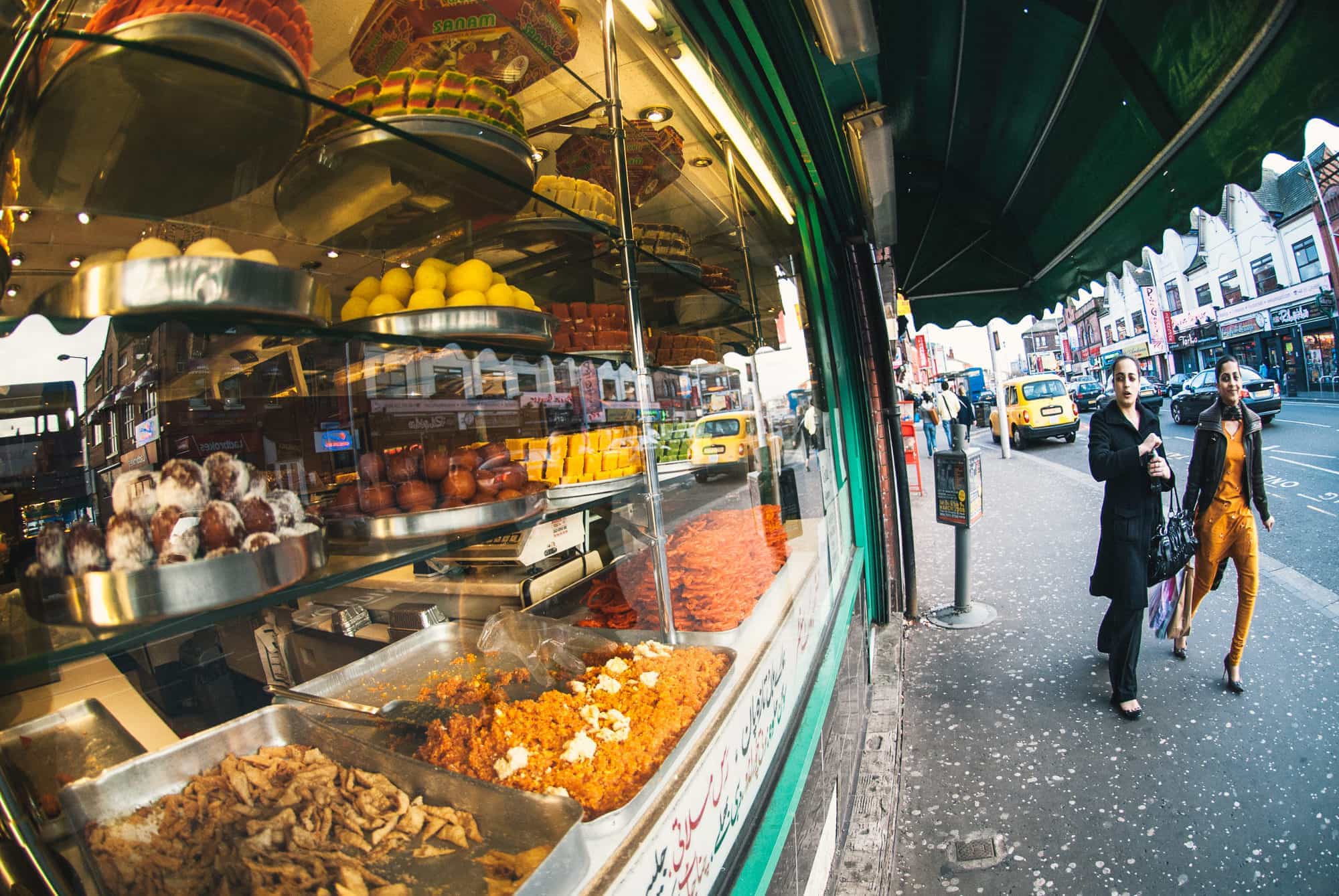 Manchester, England - Two girls pass in front of a sweets shop along Curry Mile.