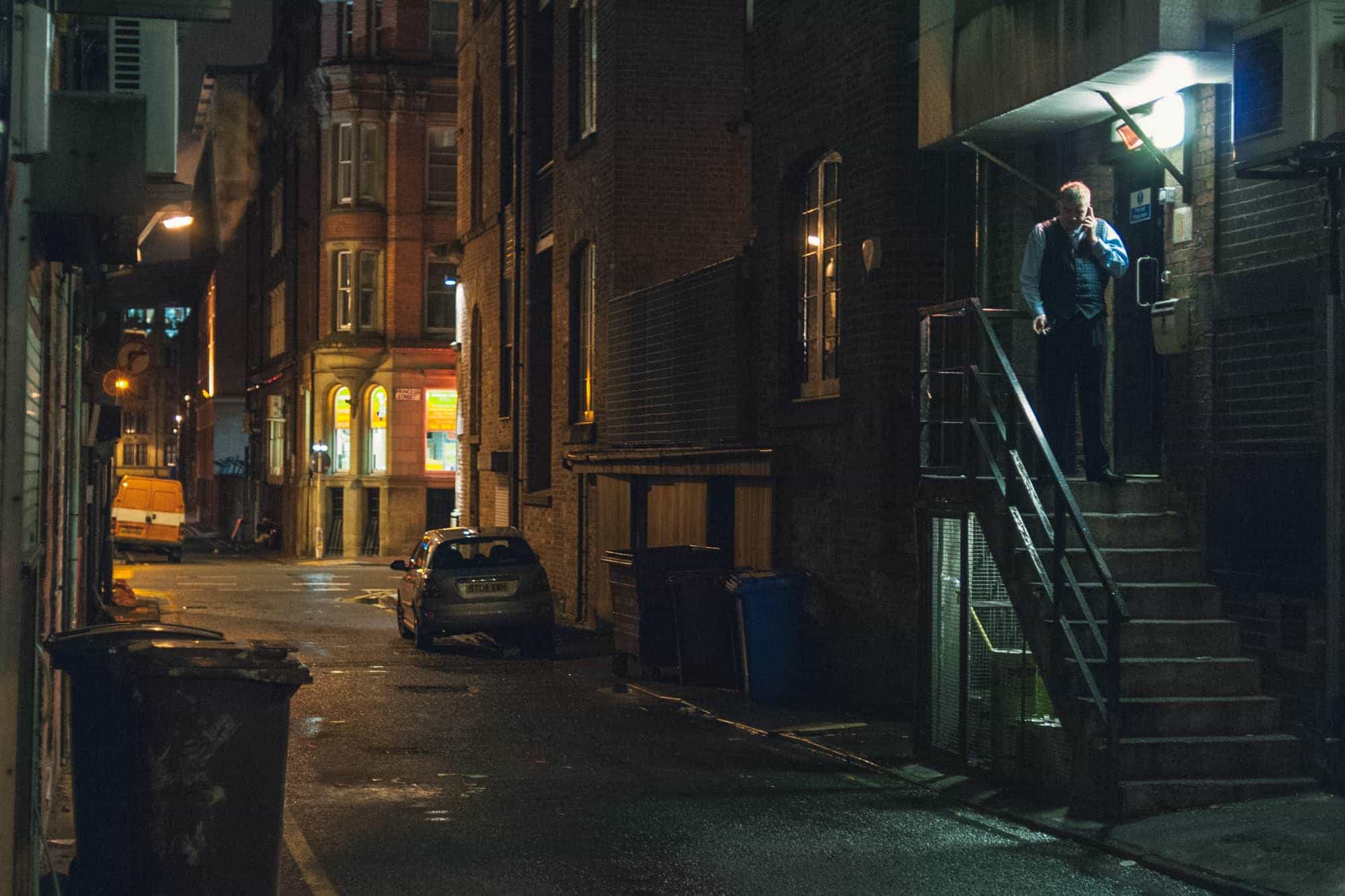 Manchester, England - Near Chinatown a man on the phone takes a smoke break in a back alley.