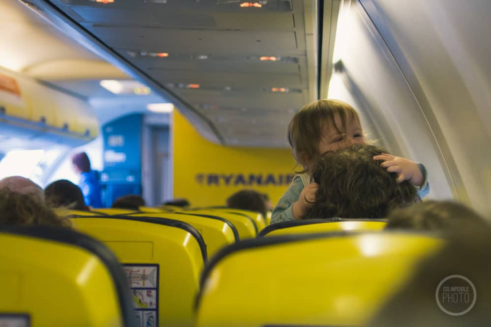 A baby crawls over mom's head aboard a Ryanair flight.