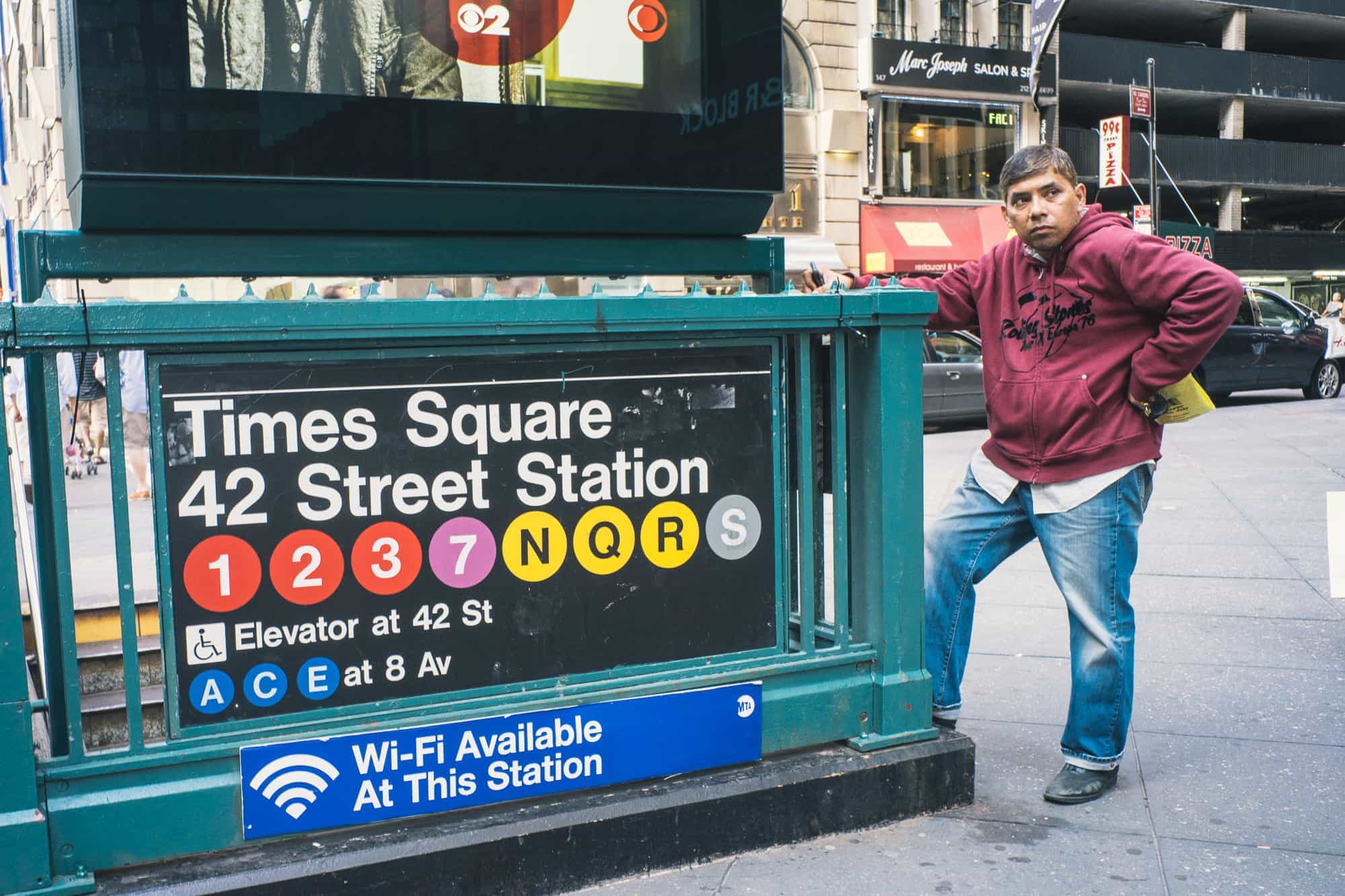 A man waits near the Time Sq 42nd street subway station sign in Time Square New York City.