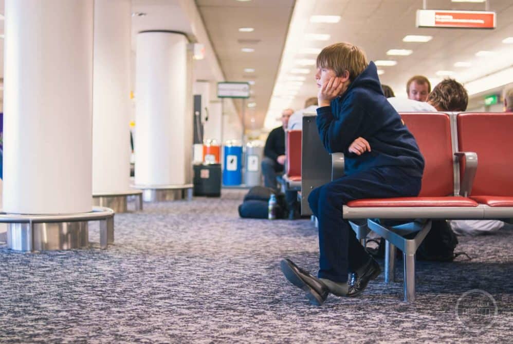 A young boy waits patiently at Heathrow Airport.