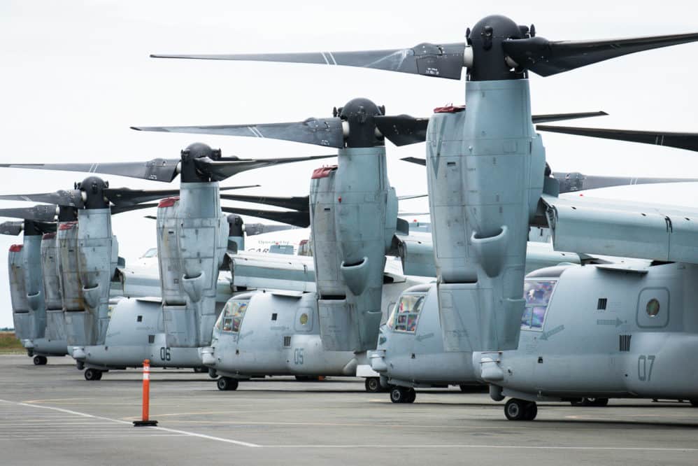 Multiple V22 Osprey line the tarmac at an airport.