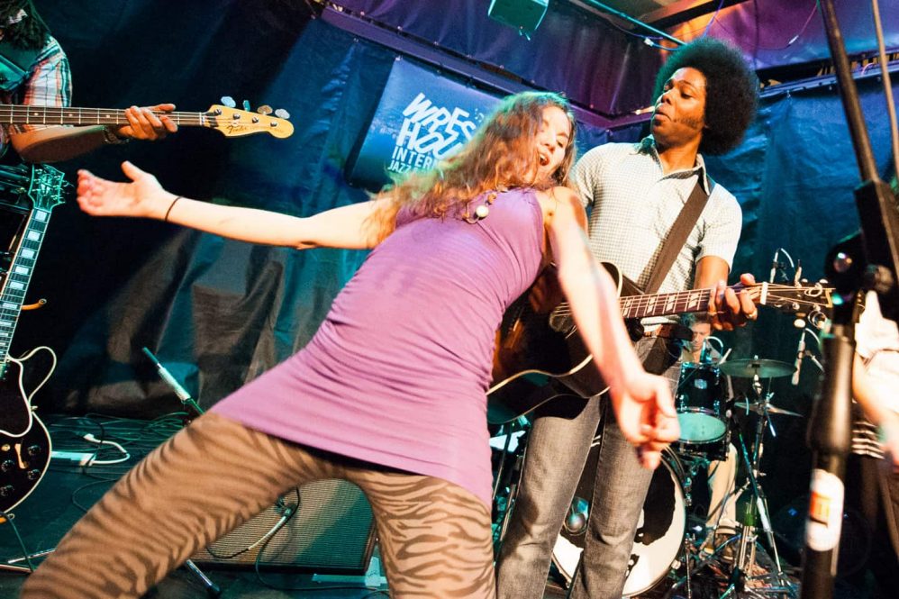 Alex Cuba peforming at the Wreckhouse Jazz and Blues Festival with a random fan dancing on stage with him.