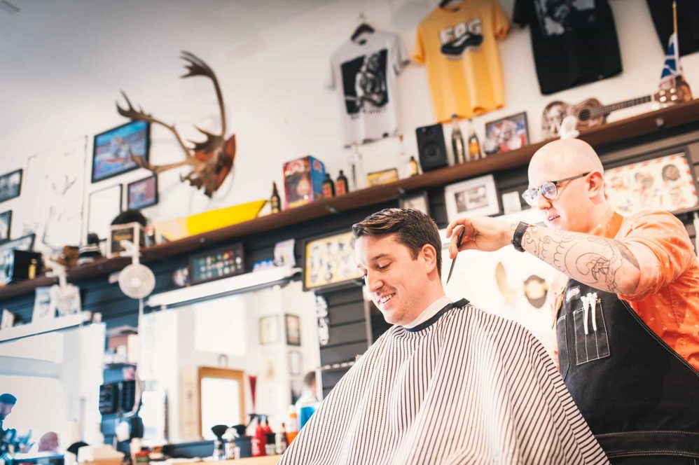 The groom gets a haircut at the barber shop on his wedding day.