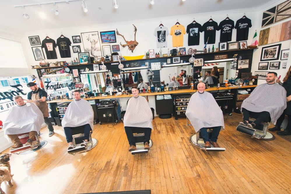 The groom, his brother and his father sit in barber chairs for a fun photograph on the morning of his wedding.