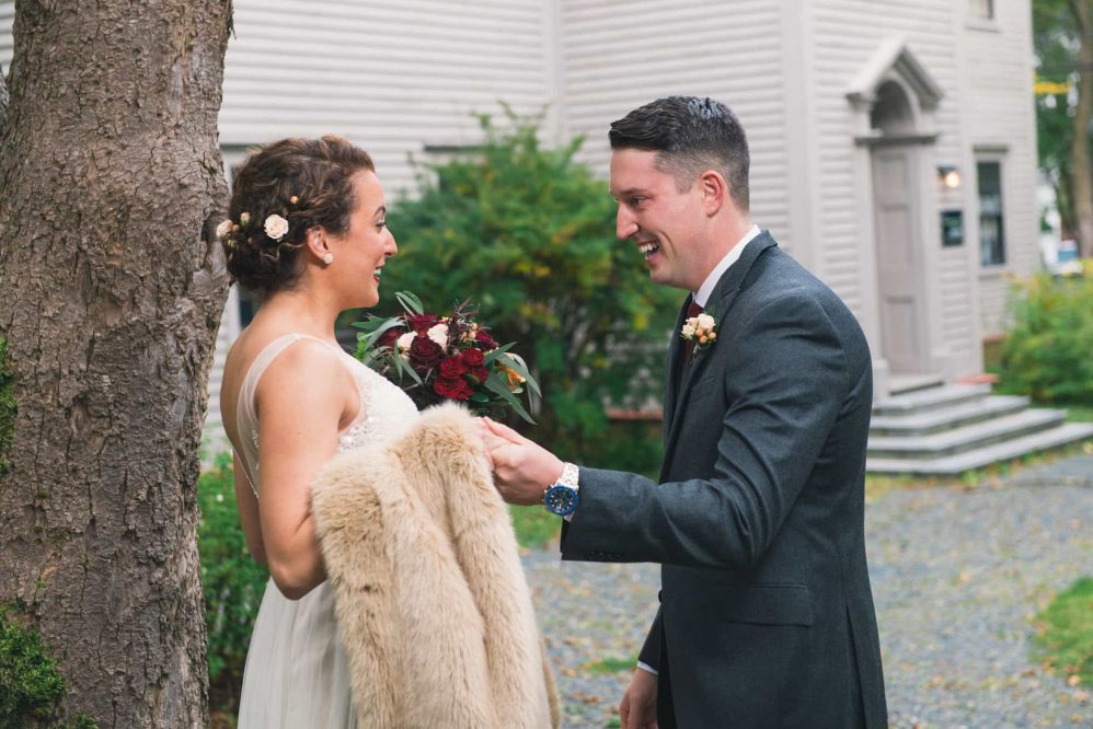 A groom holds his bride-to-be's hand as they share their first glimpse of one another on their wedding day.