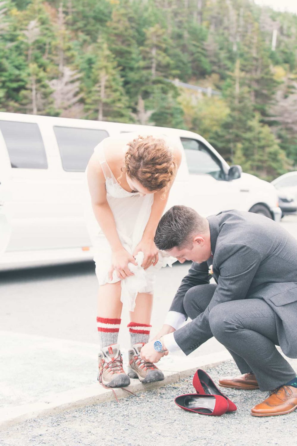 A groom aides his bride with her shoes.
