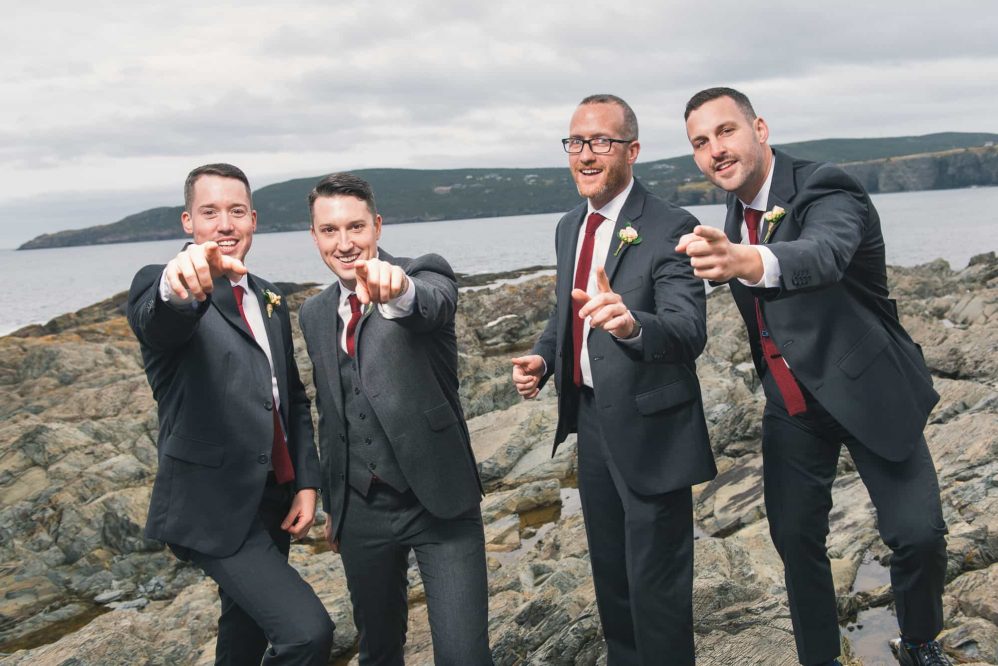 A group of groomsmen sarcastically pose for photographs like a early 2000s boy band