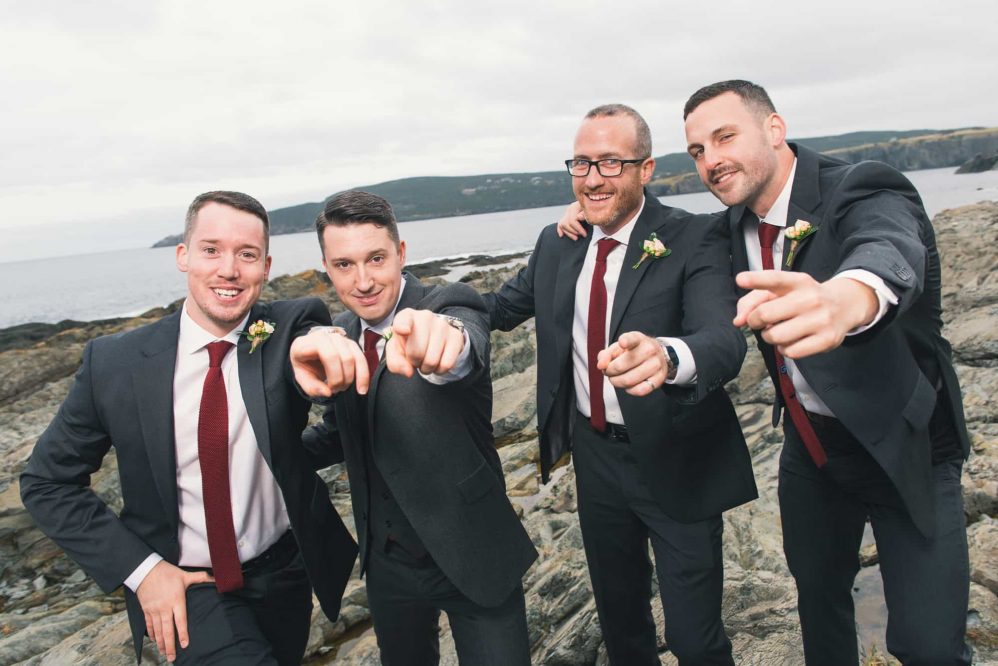 A group of groomsmen sarcastically pose for photographs like a early 2000s boy band