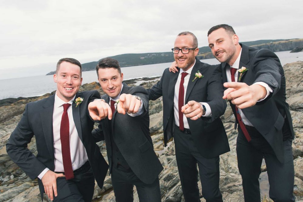 A group of groomsmen sarcastically pose for photographs like a early 2000s boy band