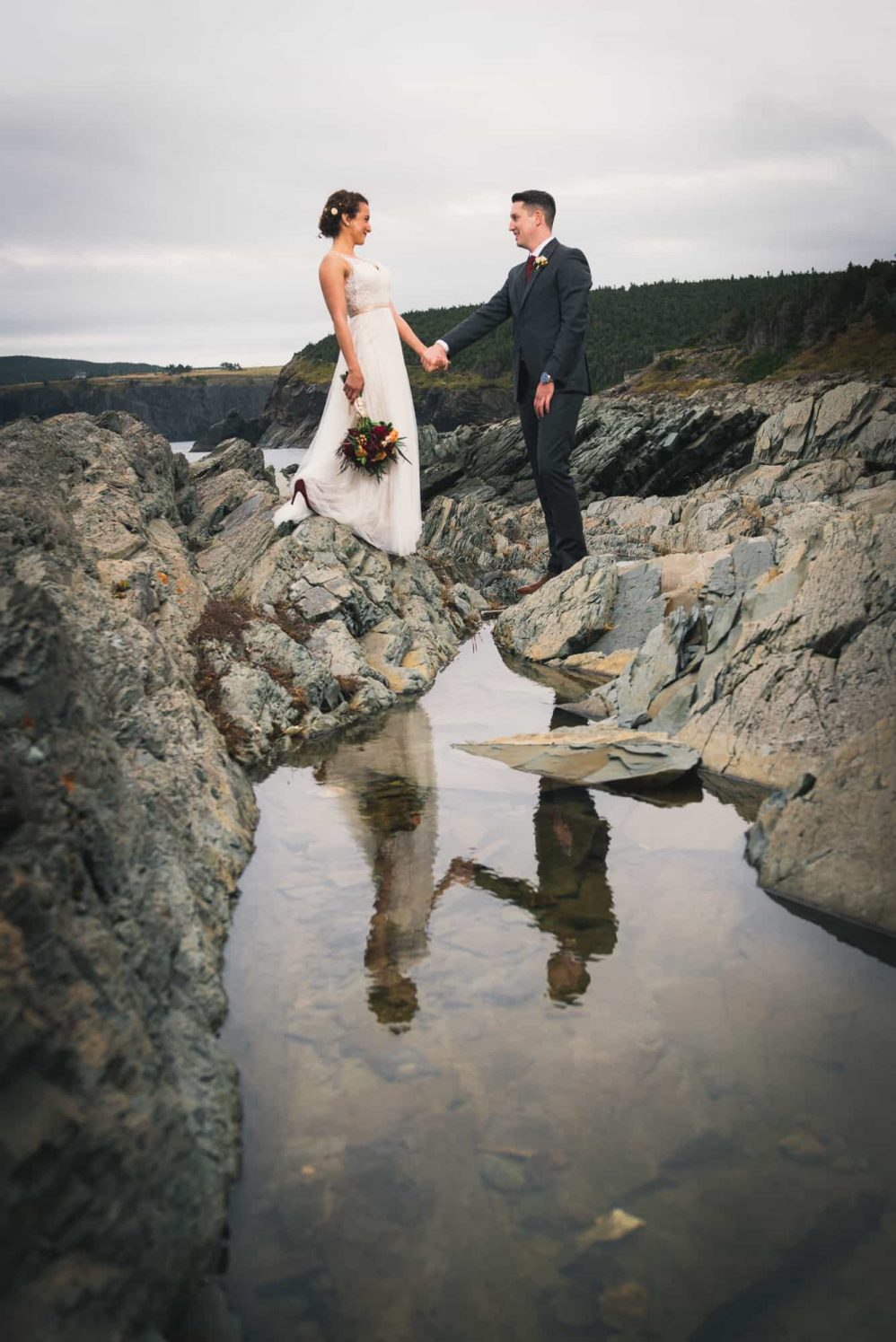 An image of the bride and groom holding hands is reflected via a foreground puddle.