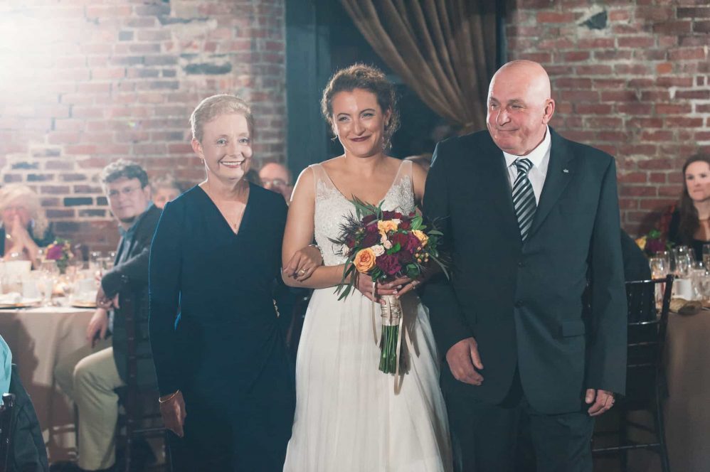 Mother and father walk their daughter down the aisle for her wedding ceremony.