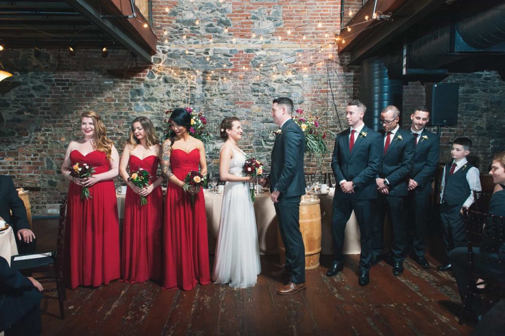 With a large stone wall in the background the whole bridal party awaits the beginning of the ceremony.