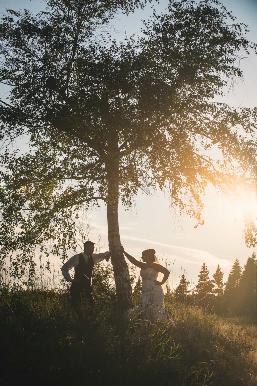 A bride and groom stare into each others eyes with the setting sun behind.