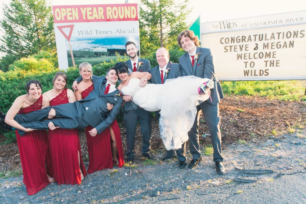 The bridal party holds the bride and groom while they kiss!