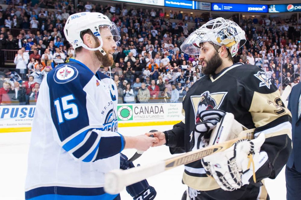 Former teammates Jason Jaffray (left) is given the game puck by Peter Manino after playoff series win for the IceCaps.