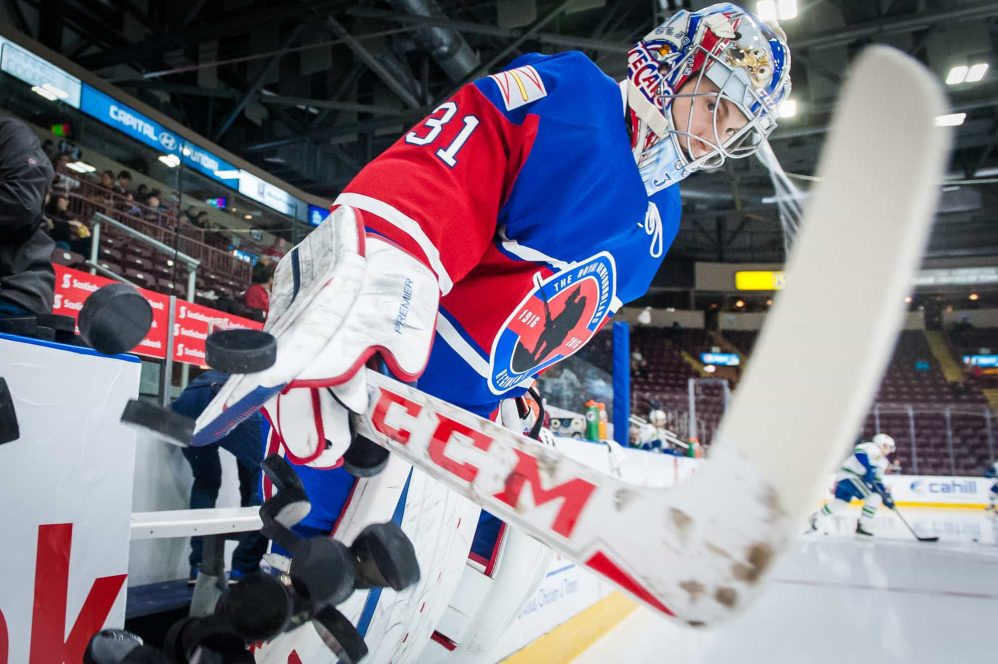 IceCaps goalie Zach Fucale clears the pucks off the ledge to start pre-game warm ups.